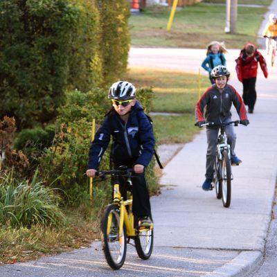 a couple of youths biking up a hill with a few more kids following them