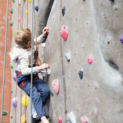 determined little boy enjoying rock climbing at indoor climbing gym, healthy and active lifestyle concept