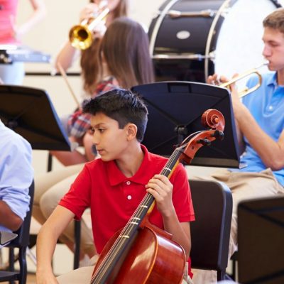 a youth playing the trumpet, one youth playing the cello another one playing the clarinet